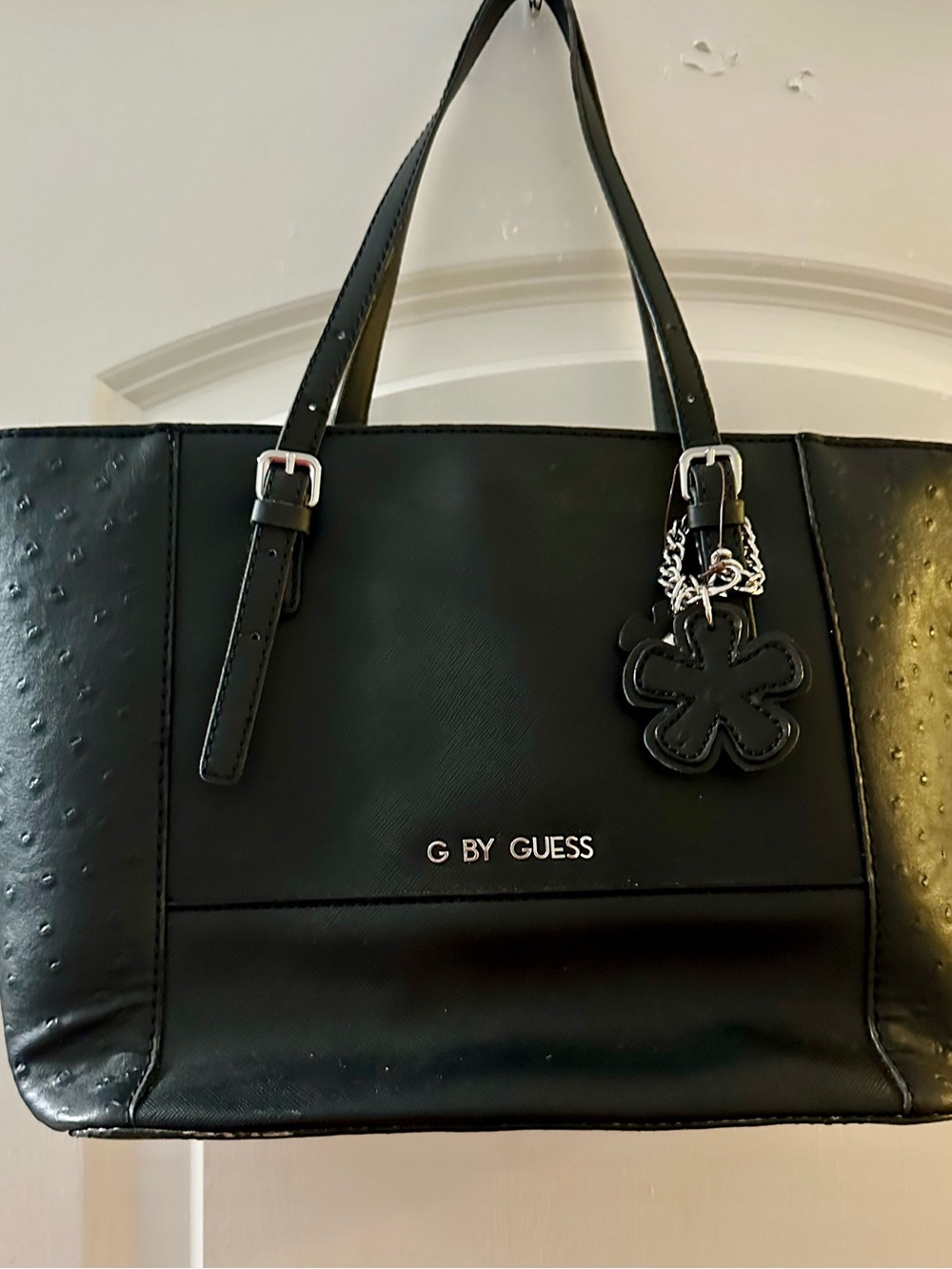 G by Guess Black Tote with Floral Charm Accent peeling on button shown in pictur